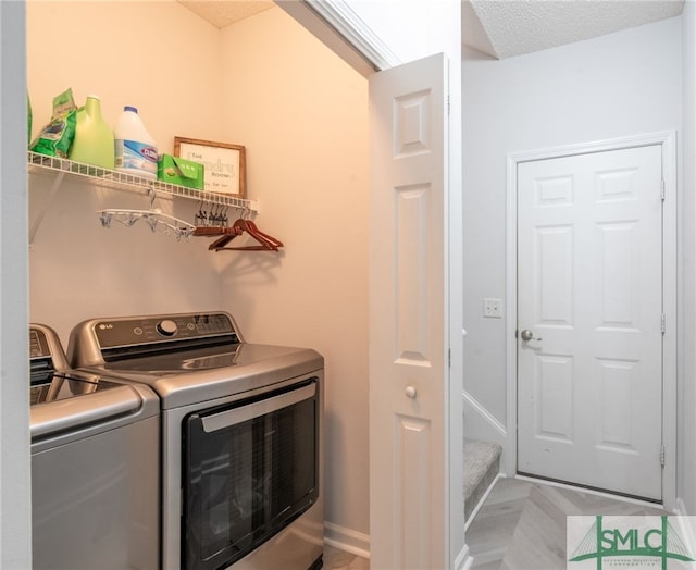 laundry room with a textured ceiling and washing machine and dryer