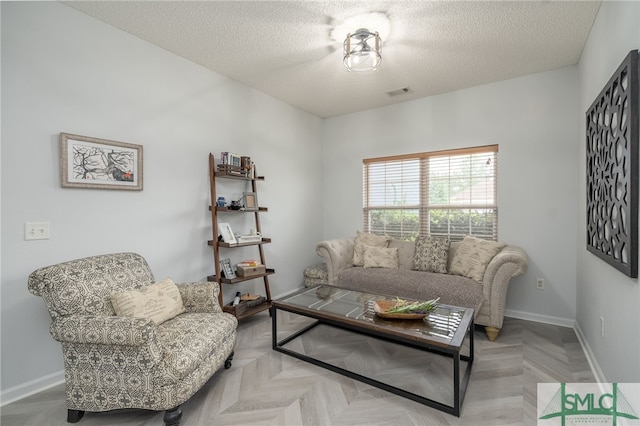 living room featuring a textured ceiling, visible vents, and baseboards