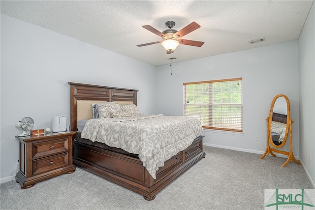 bedroom with a textured ceiling, visible vents, light colored carpet, and baseboards