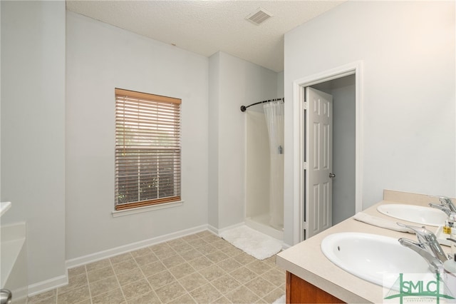 bathroom featuring vanity, a textured ceiling, curtained shower, and tile patterned flooring