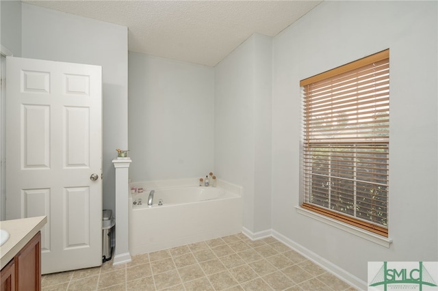 bathroom featuring a garden tub, a textured ceiling, and vanity