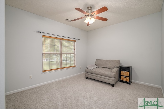 living area with a textured ceiling, light colored carpet, and ceiling fan