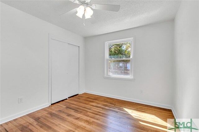 empty room featuring ceiling fan, a textured ceiling, and light wood-type flooring