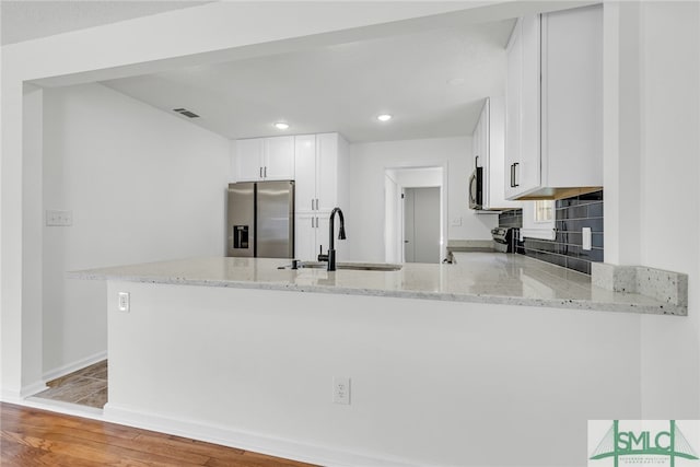 kitchen with kitchen peninsula, white cabinetry, light wood-type flooring, sink, and stainless steel appliances