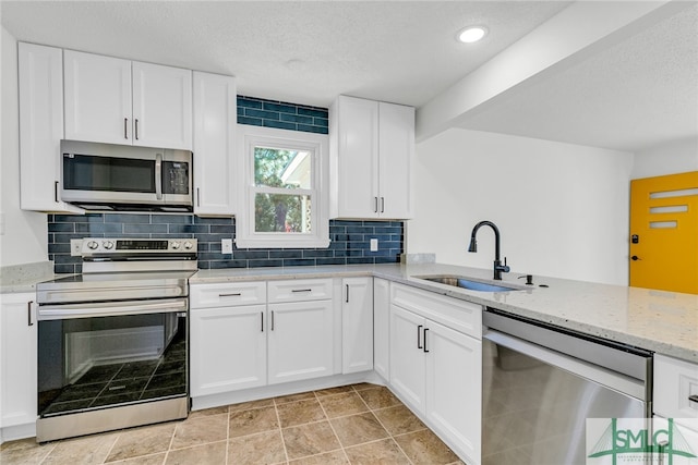 kitchen featuring tasteful backsplash, appliances with stainless steel finishes, sink, and white cabinets