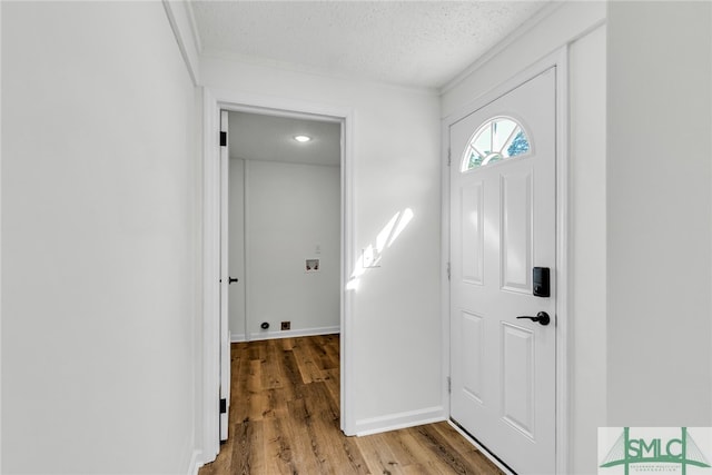 foyer with a textured ceiling, crown molding, and hardwood / wood-style flooring