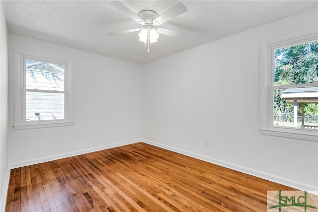 empty room featuring ceiling fan, a textured ceiling, plenty of natural light, and hardwood / wood-style floors