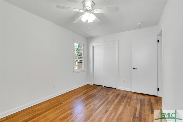 unfurnished bedroom with a textured ceiling, wood-type flooring, a closet, and ceiling fan