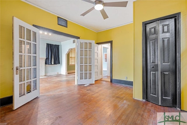 empty room featuring ceiling fan, french doors, wood-type flooring, and ornamental molding