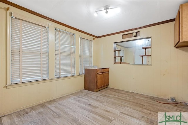 spare room featuring light wood-type flooring and crown molding