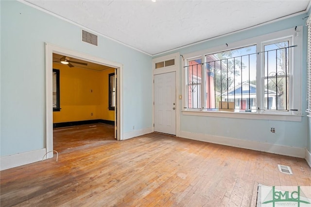 empty room featuring ceiling fan, light hardwood / wood-style floors, and crown molding