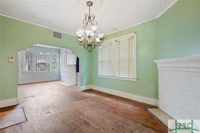 unfurnished dining area with hardwood / wood-style floors, a healthy amount of sunlight, ornamental molding, and an inviting chandelier