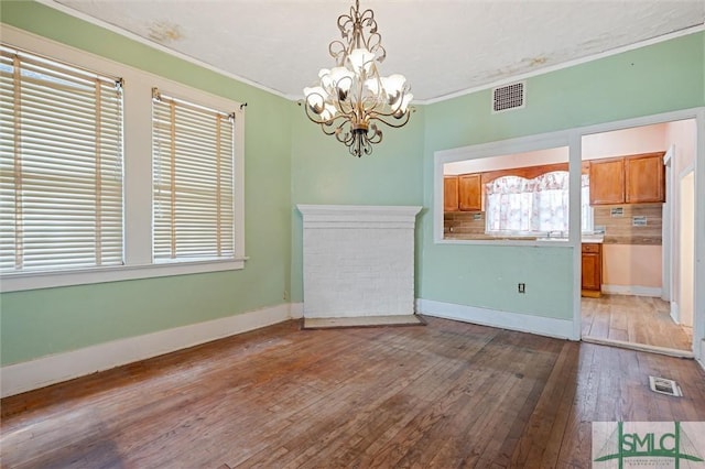 unfurnished dining area featuring crown molding, hardwood / wood-style floors, and an inviting chandelier