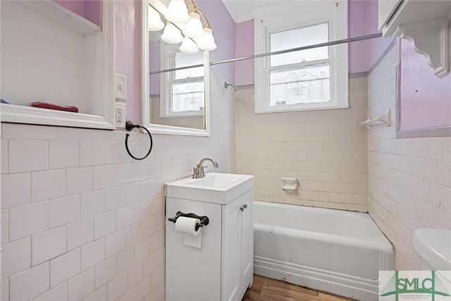 full bathroom with toilet, hardwood / wood-style flooring, vanity, tile walls, and tiled shower / bath