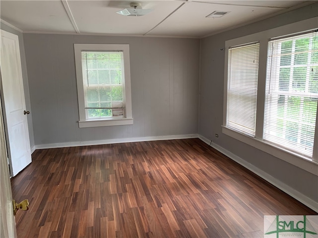 spare room with dark hardwood / wood-style flooring, wooden walls, ceiling fan, and crown molding