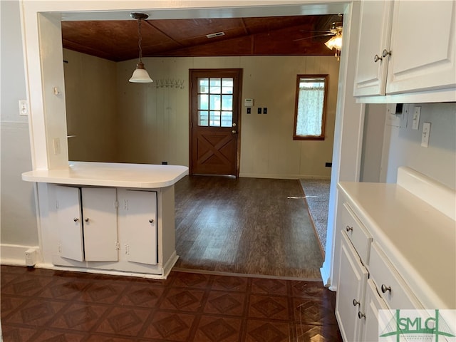 kitchen with white cabinetry, ceiling fan, wood walls, decorative light fixtures, and vaulted ceiling