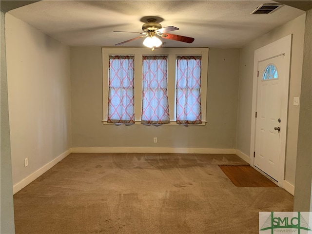 carpeted entryway with ceiling fan and a textured ceiling