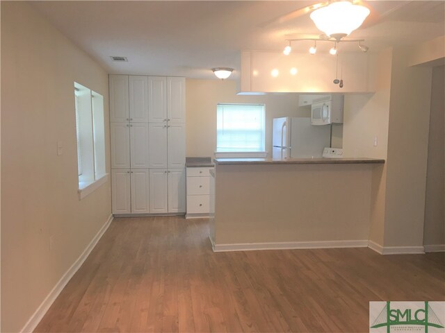 kitchen with white cabinets, white appliances, and dark wood-type flooring