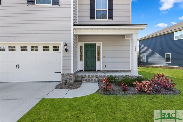 entrance to property featuring a lawn and a garage