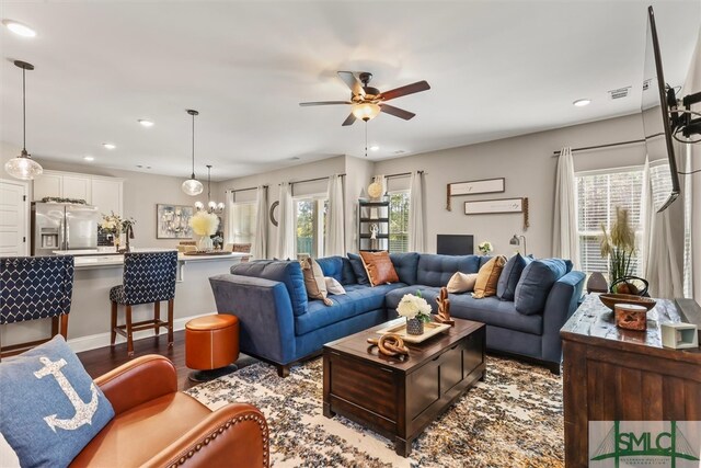 living room featuring hardwood / wood-style floors, ceiling fan with notable chandelier, and plenty of natural light