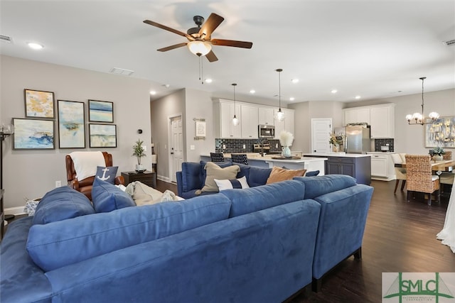 living room with dark wood-type flooring and ceiling fan with notable chandelier