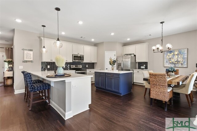 kitchen featuring kitchen peninsula, blue cabinets, stainless steel appliances, pendant lighting, and a breakfast bar area