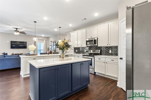 kitchen featuring dark hardwood / wood-style floors, hanging light fixtures, kitchen peninsula, a barn door, and appliances with stainless steel finishes