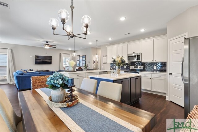 kitchen featuring appliances with stainless steel finishes, a kitchen island, kitchen peninsula, pendant lighting, and white cabinets