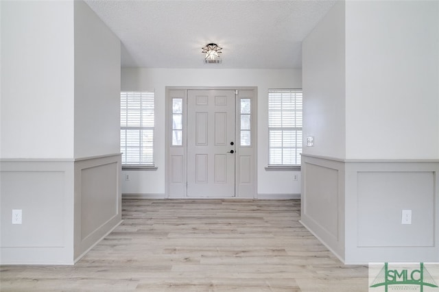 entryway with light hardwood / wood-style floors and a textured ceiling