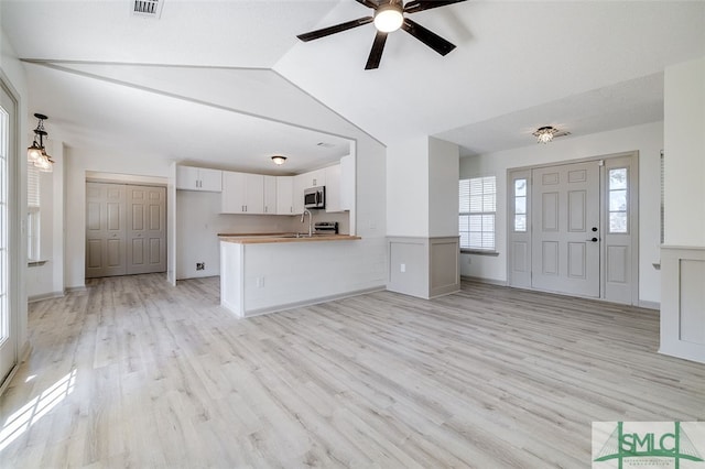 interior space with sink, vaulted ceiling, light hardwood / wood-style flooring, and ceiling fan