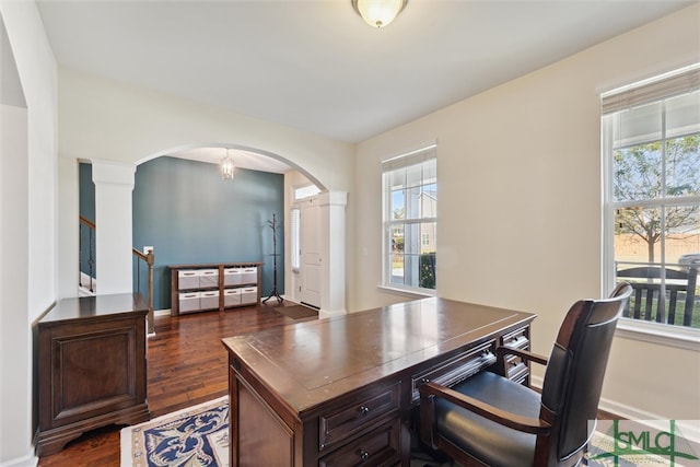 office with dark wood-type flooring, ornate columns, and a healthy amount of sunlight