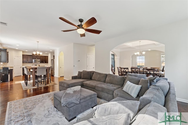 living room featuring dark hardwood / wood-style flooring and ceiling fan with notable chandelier