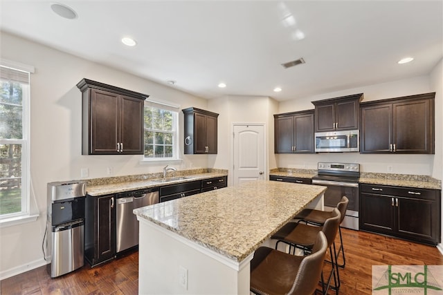 kitchen with a wealth of natural light, a center island, appliances with stainless steel finishes, and dark wood-type flooring