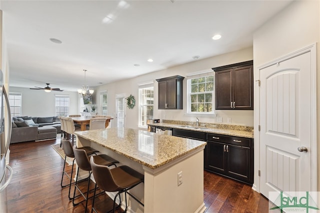 kitchen featuring dark hardwood / wood-style floors, hanging light fixtures, a center island, a kitchen bar, and dark brown cabinetry