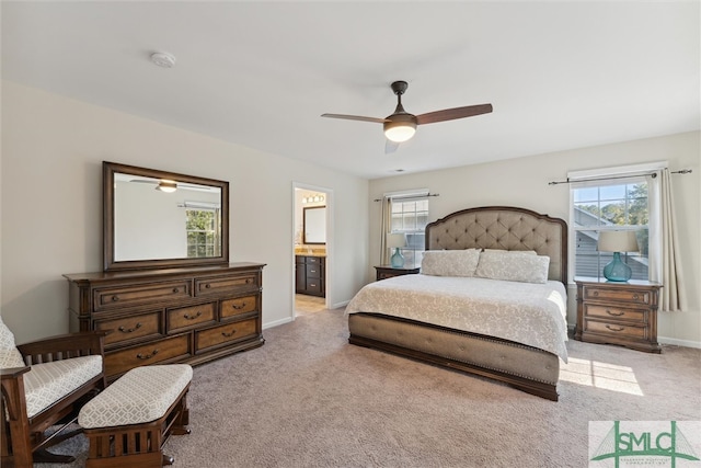 bedroom with connected bathroom, ceiling fan, multiple windows, and light colored carpet