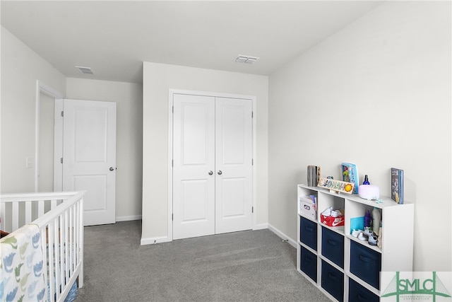 bedroom featuring a nursery area, dark colored carpet, and a closet