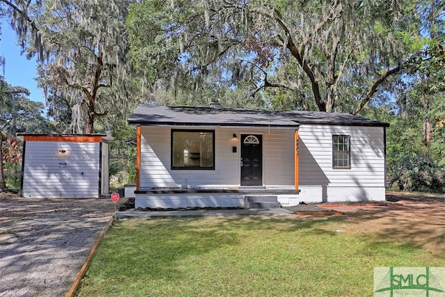 view of front of property featuring covered porch, a front yard, and a storage unit