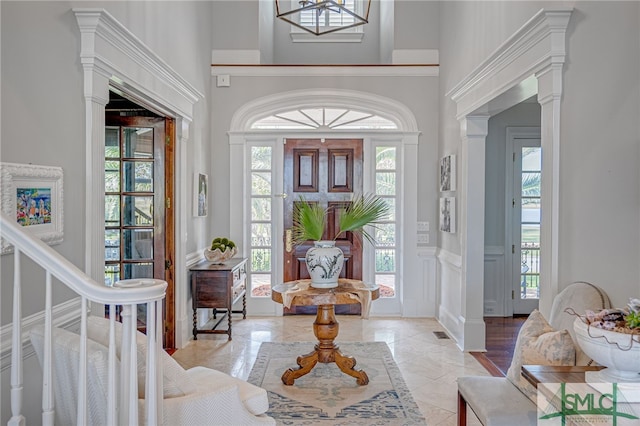 entrance foyer featuring a wealth of natural light, a chandelier, and ornate columns