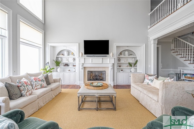 living room featuring built in shelves, a high ceiling, and hardwood / wood-style flooring