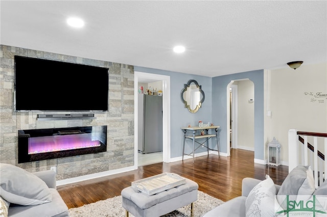 living room with a stone fireplace and wood-type flooring