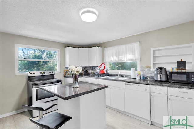 kitchen featuring white dishwasher, a kitchen island, white cabinets, and stainless steel electric stove