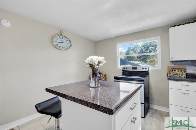 kitchen featuring white cabinets, stainless steel range with electric cooktop, a breakfast bar, a textured ceiling, and a center island