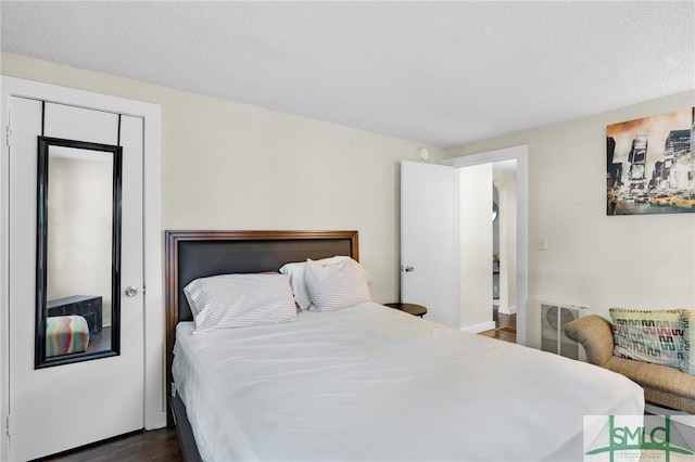 bedroom with a closet, a textured ceiling, and dark hardwood / wood-style flooring