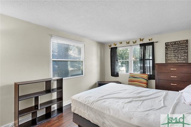 bedroom with a textured ceiling and dark hardwood / wood-style floors