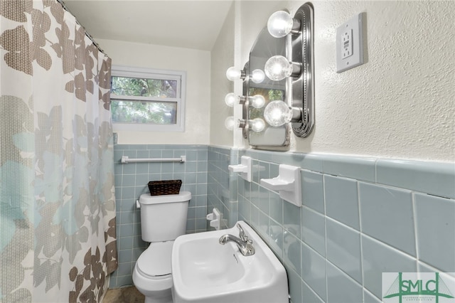 bathroom with tile walls, sink, a shower with curtain, and toilet