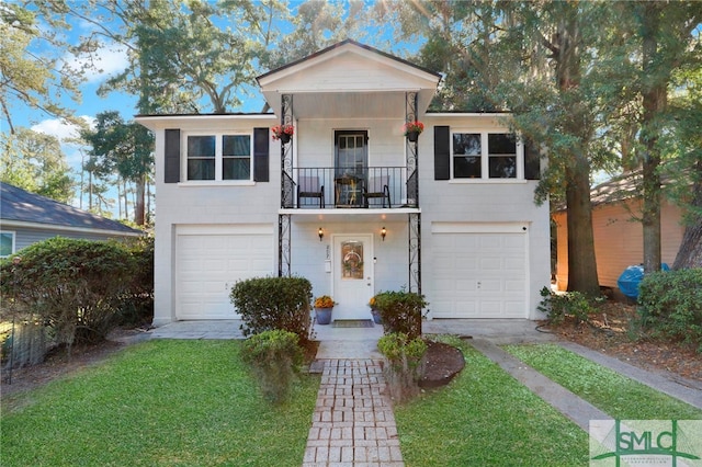 view of property featuring a front yard, a balcony, and a garage