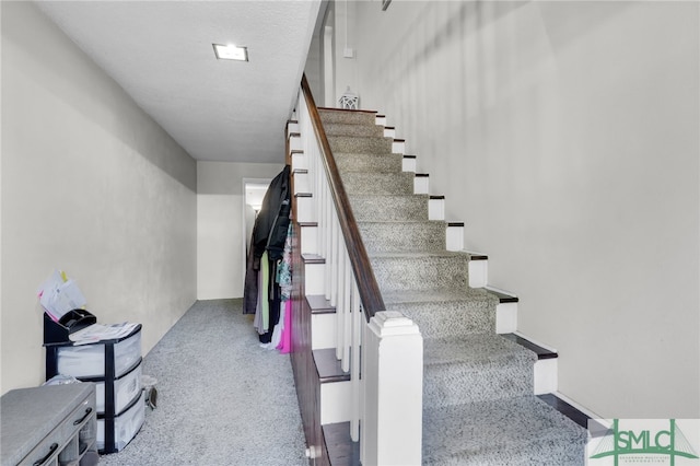 stairway featuring carpet and a textured ceiling