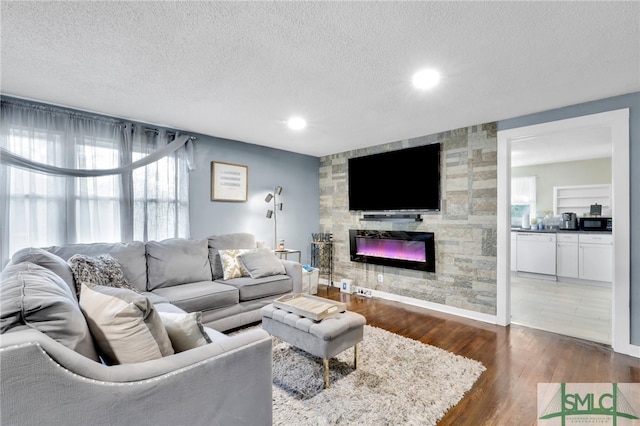 living room featuring dark wood-type flooring, a fireplace, a textured ceiling, and plenty of natural light