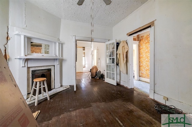 interior space featuring ceiling fan, dark hardwood / wood-style flooring, a textured ceiling, and a brick fireplace