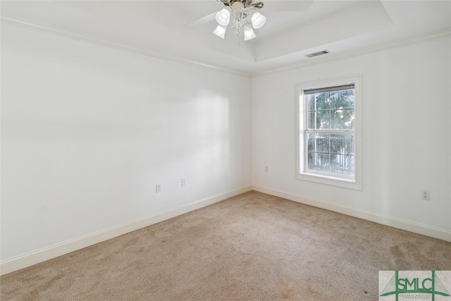 carpeted empty room with crown molding, a raised ceiling, and ceiling fan